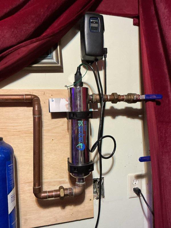 Completed comprehensive VIP maintenance inspection including tankless water heater, sump pump, and whole-home plumbing system evaluation. Inspected and verified proper operation of UV water purification system with clear housing showing active filtration media, confirmed electrical controls functioning correctly with illuminated indicators, and examined all copper piping connections and brass fittings for integrity. Tested ball valve operation, verified secure mounting of filtration components to wall backing, and confirmed power supply connections to UV purifier and control units were secure and operational.