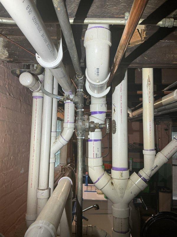 Inspected and documented existing plumbing infrastructure in crawl space and basement areas. The inspection revealed a mixed plumbing system consisting of copper supply lines, white PVC drainage piping, and older galvanized steel components. Copper piping showed typical patina and discoloration consistent with age but remained structurally sound with proper support brackets and connections. PVC drainage system appeared to be newer installation with appropriate slope and connection points. All visible pipe joints, valves, and fittings were examined for proper function and integrity. Photographs were captured to document current system configuration and condition for customer records.