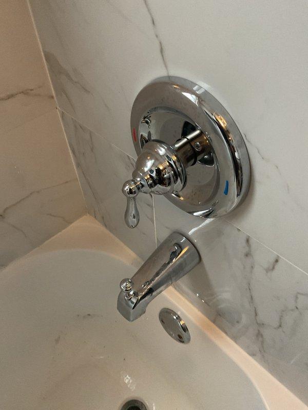 Responded to service call for dripping bathroom faucet. Disassembled single-handle tub/shower valve assembly and removed worn cartridge from chrome fixture mounted on marble-patterned tile wall. Replaced faulty cartridge, internal springs, and seals to eliminate leak. Reassembled valve assembly, tested operation for proper flow control and verified complete elimination of drip. System restored to full functionality.