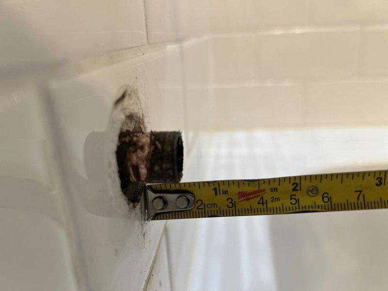 Responded to water leak complaint from downstairs unit reporting ceiling water intrusion originating from master bathroom area. Upon inspection, identified corroded and deteriorating tub drain assembly with visible rust, water staining, and compromised seals at the fixture-to-tile interface. Evidence of chronic moisture penetration was observed in surrounding grout lines and tile corners, with active dampness detected on subfloor beneath bathtub access panel. The leak was triggered by draining bathwater, indicating failed drain gasket or compromised plumbing connection allowing water to bypass the drain system and seep through the floor assembly to the unit below.