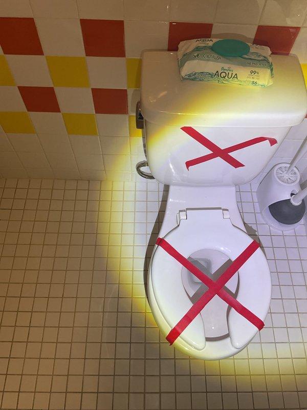 Responded to report of leak at base of toilet in commercial restroom facility. Upon inspection, discovered severely deteriorated floor drain with extensive rust, corrosion, and mineral buildup contributing to water damage and yellow staining on surrounding tile floor. Evaluated toilet fixture which exhibited signs of base seal failure. Removed and reset toilet with new wax ring and closet bolts to eliminate leak at base connection. Tagged toilet out of service during repair process. Addressed floor drain deterioration and verified proper sealing of toilet base to prevent further water infiltration and tile damage.