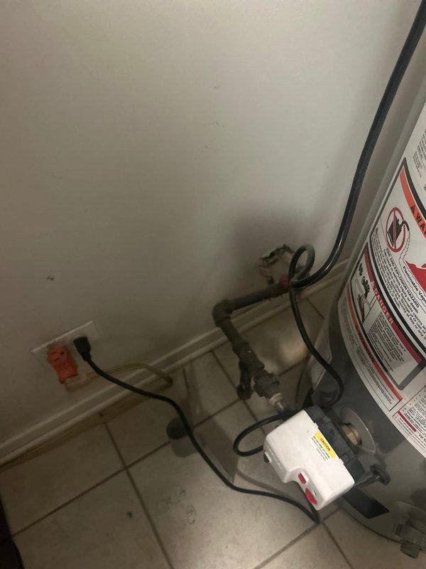 Responded to service call for plumbing system evaluation in residential utility closet. Inspected water heater installation and associated piping connections, including PVC supply lines with brass fittings, copper circulation pipes, and valve assemblies. Documented existing system configuration showing dark-colored mechanical equipment with multiple pipe connections and yellow-handled valve control. Identified ceiling discoloration above water heater indicating potential previous moisture intrusion or heat-related issues requiring monitoring. Verified electrical connections and outlet functionality for water heating equipment. Photographed complete installation for service records, capturing plumbing connections, equipment condition, and environmental concerns for future reference and maintenance planning.