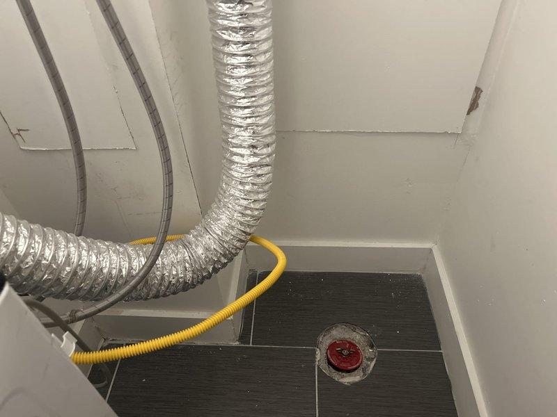 Relocated gas and water supply lines to accommodate new washer and dryer placement. Installed recessed washing machine outlet box with hot and cold water connections using braided stainless steel flexible supply lines. Rerouted gas line using yellow corrugated flexible conduit and coordinated electrical conduit placement to ensure proper clearances and code compliance for the laundry appliance installation.