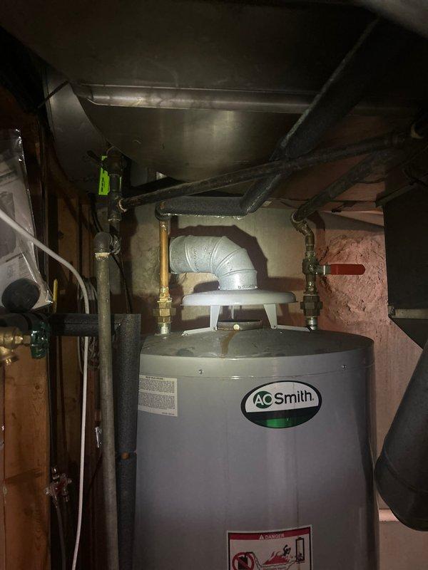 Completed installation of A.O. Smith residential water heater in basement utility area. Connected hot and cold water supply lines using copper piping with brass shut-off valves and fittings, installed ICON System gas valve control unit with proper temperature settings, and verified all plumbing connections for proper operation. Unit tested and confirmed operational with gas pilot light functioning and all safety features in place.