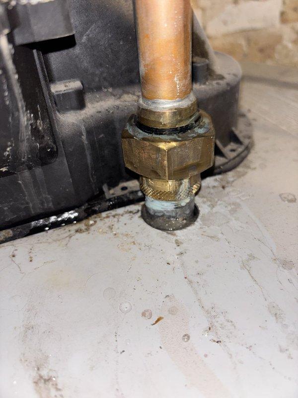 Responded to service call for tanked water heater installed in 2023 that was leaking from top connections and failing to heat water. Upon inspection, identified significant corrosion and mineral deposits on copper pipe connections and brass compression fittings at the top of the unit, with visible white-green oxidation residue indicating prolonged moisture exposure at the threaded joints. Documented the failed connections showing deteriorated gaskets and compromised seals that were allowing water to leak from the inlet/outlet plumbing connections.
