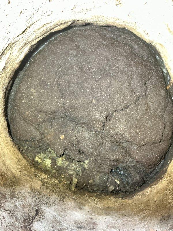 Completed plumbing repair for sold service call. Accessed and repaired sewer cleanout access point that showed signs of previous water infiltration and deterioration. The cleanout opening had compromised sealing material with visible cracking in the existing patching compound. Removed old deteriorated sealant and mortar material from around the cleanout perimeter. Cleaned and prepared the surface for proper resealing. Applied new patching compound and installed fresh perimeter sealing material to prevent future water infiltration and maintain proper access point integrity. The exterior walkway area adjacent to the repair location showed moisture accumulation and algae growth on surrounding surfaces, indicating drainage concerns in the vicinity. Ensured cleanout access remains functional while providing weathertight seal to prevent groundwater intrusion into the sewer system. Documented completed work with photographs for service records.