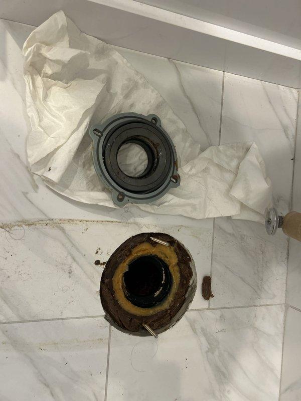 Responded to commercial facility for clogged drain system. Upon inspection, discovered severely corroded pump bearing and mounting flange causing drainage failure. Removed heavily deteriorated components exhibiting extensive rust damage and mineral buildup. The existing flange showed significant corrosion around the central opening with substantial debris accumulation in the drain cavity. Replaced failed bearing assembly and corroded mounting hardware with new components. Cleared thick oily sludge and black residue from drain access point. Restored proper drainage function and tested system operation to ensure complete resolution.
