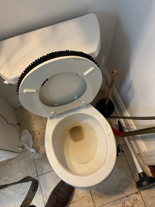 Responded to a clogged toilet service call and successfully cleared the blockage using a plunger. Upon arrival, found the toilet bowl filled with dark, murky water indicating a complete obstruction in the drain line. Applied proper plunging technique to dislodge the clog, restoring normal water flow and drainage function. Tested the toilet flush mechanism multiple times to confirm the blockage was fully cleared and proper operation was restored.