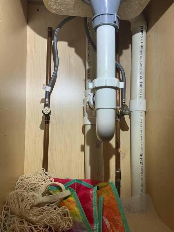 Completed plumbing estimate for reverse osmosis water filtration system installation at residential kitchen sink location. Assessed existing under-sink plumbing configuration including PVC drain assembly, copper supply lines, and PEX connections to determine optimal mounting position and water supply tie-in points for RO system installation.