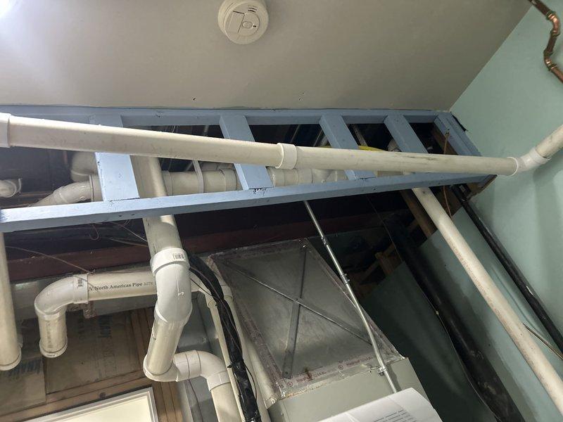 Responded to emergency service call for leaking water heater with reduced hot water capacity at residential property. Removed existing failed tanked water heater and installed new wall-mounted tankless water heater unit on backing board with proper copper supply line connections and electrical hookup. Completed initial installation including hot and cold water piping, electrical connection to dedicated outlet, and partial venting system installation. White PVC venting pipes routed through ceiling area and structural spaces. Installation requires follow-up visit to complete intake and exhaust venting penetration through foundation exterior wall. Unit temporarily operational pending final vent termination completion.
