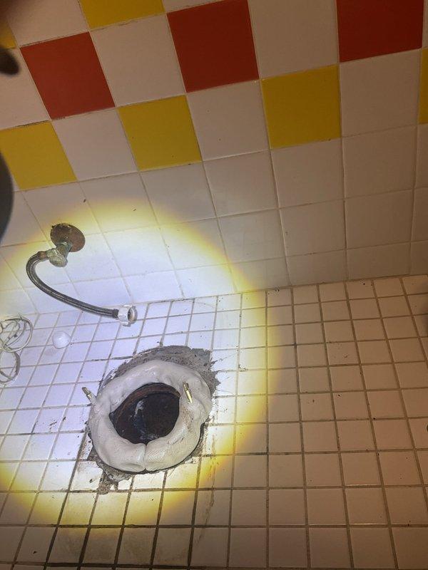 Responded to service call for toilet leak and drain backup issue. Upon arrival, discovered significant water infiltration and drainage problems in bathroom area. Inspected floor drain and toilet connection, observing discoloration and staining around fixtures indicating chronic moisture issues and potential sewage backup. Identified compromised grout lines and tile sealant allowing water penetration. Assessed flexible water supply line condition and verified proper connections. Documented existing conditions including yellowing and staining on floor tiles surrounding drain and toilet base, consistent with prolonged exposure to wastewater. Photographed affected areas showing deteriorated grout, mineral deposits, and biological staining patterns. Evaluated shower floor drain for potential cross-contamination or shared drainage concerns. Determined root cause of backup and leaking, likely due to partial blockage in main drain line or failed wax ring seal at toilet base allowing wastewater
