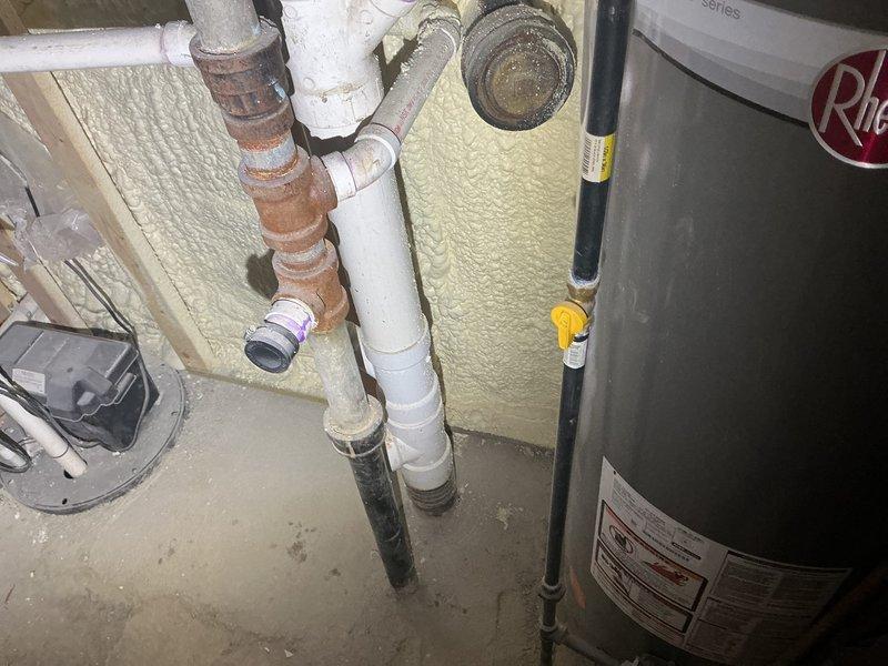 Replaced aging water heater system in basement utility area due to severe corrosion of existing metal piping and deteriorating unit condition. Removed old corroded brown metal pipes and installed new water heater with updated plumbing connections, including white PVC drainage lines and copper supply lines. Connected metallic exhaust vent ductwork to top of unit and ensured proper venting through existing infrastructure. All installations completed to current plumbing code standards with appropriate safety labeling and manufacturer specifications verified.