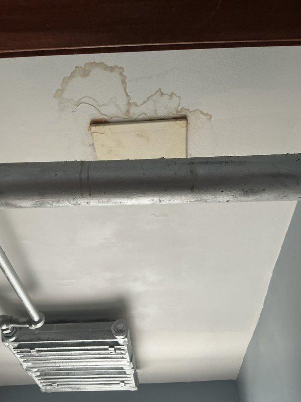 Responded to building water damage emergency during scheduled shutdown period. Upon inspection, identified active leak affecting ceiling and wall surfaces in mechanical utility area near HVAC equipment. Water infiltration had caused significant paint deterioration, bubbling, and separation from substrate, with exposed drywall visible in affected zones. Traced source of leak to compromised PVC piping running horizontally above damaged area. Isolated water supply, repaired defective pipe section, and verified system integrity through pressure testing. Applied temporary ceiling patch to contain damaged drywall area and prevent further deterioration until cosmetic restoration can be completed. Confirmed no water intrusion to adjacent HVAC heat exchanger components or associated metallic tubing. System restored to full operation following successful repairs.
