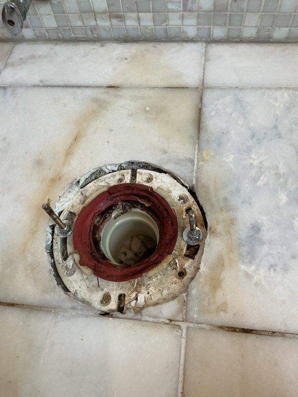 Responded to water leak investigation request from upper-unit resident after multiple lower units reported bathroom ceiling leaks. Conducted thorough inspection of bathroom plumbing fixtures and surrounding areas to determine if unit was the source of water intrusion. Visual examination revealed significant deterioration of toilet flange seal with heavy rust corrosion and staining on surrounding floor tiles, indicating potential leak point. Shower enclosure corner showed moisture-related discoloration, rust staining on metal door track components, and water spotting on wall tiles. Documented all findings with photographs showing compromised toilet seal with rust-colored gasket deterioration and mineral deposits radiating from drain area, as well as corner moisture damage and oxidation of shower door hardware. Provided photographic evidence to confirm presence of potential leak sources requiring repair to prevent continued water damage to units below.