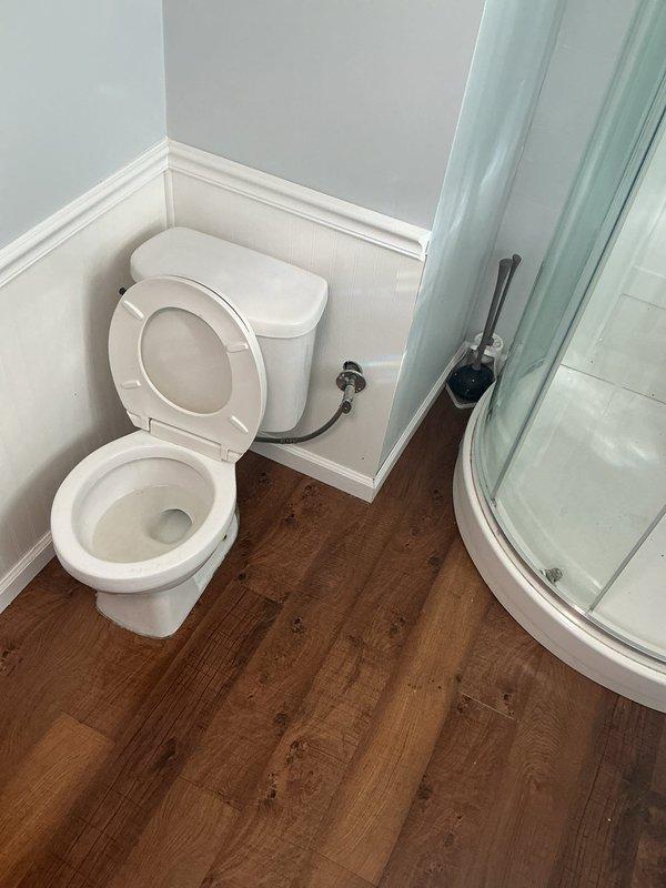 Responded to plumbing service call and performed comprehensive inspection of toilet and drainage system. Identified debris accumulation in floor drain opening and potential drainage concerns. Documented existing conditions of bathroom fixtures including toilet, shower enclosure, and plumbing connections. Presented repair options and sold necessary plumbing services to address drainage issues and ensure proper system function.