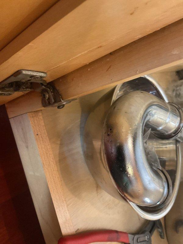 Responded to water leak under kitchen sink. Upon inspection, identified leaking P-trap assembly with visible corrosion and compromised seal connections. Disassembled chrome-plated P-trap, cleaned all connection points, and replaced worn washers and slip joint gaskets. Reassembled drain assembly with proper alignment and torque specifications. Tested system under full water flow to verify leak resolution and proper drainage. Cabinet interior showed minor water staining on wall panel, indicating previous moisture exposure now resolved.