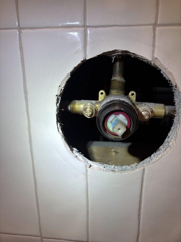 Responded to complaint of extremely low water pressure in upstairs shower, with hot water reduced to barely a trickle and cold water flow significantly restricted, while adjacent sink maintained normal pressure. Accessed shower valve assembly by creating opening in tile wall to diagnose pressure restriction issue. Upon inspection, identified pressure-balancing valve as source of flow limitation. Replaced faulty shower valve cartridge and pressure-balancing mechanism to restore proper water flow to both hot and cold water lines. Tested system operation to verify adequate pressure restoration and proper temperature control function. Completed installation with all fixtures operational and water pressure normalized throughout the shower system.