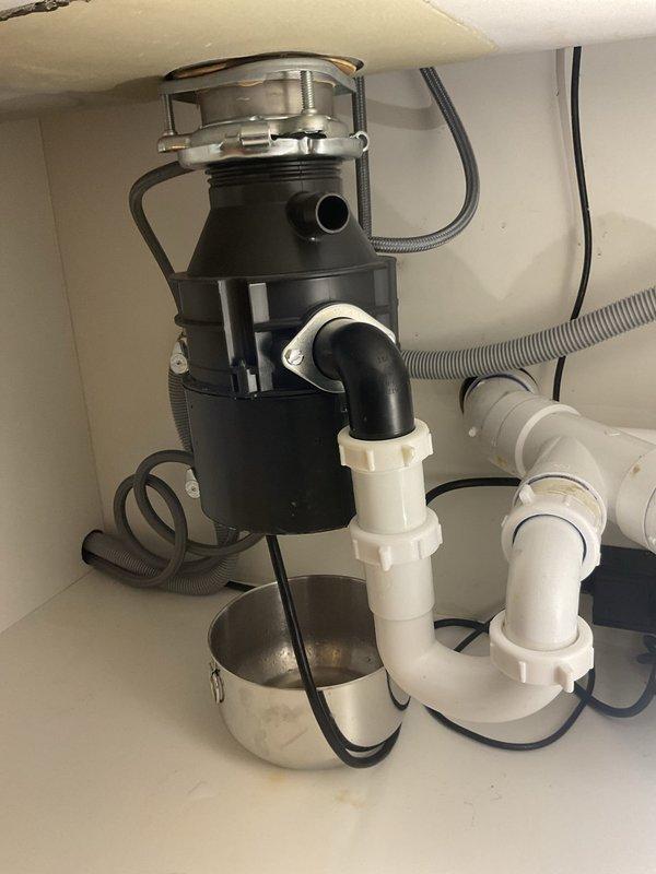 Responded to service call for garbage disposal repair. Upon arrival, performed comprehensive inspection of the disposal unit and associated plumbing assembly beneath the kitchen sink. Evaluated the black garbage disposal unit, mounting assembly, and all connected components including the P-trap configuration, drainage hoses, and electrical connections. Verified proper operation of the disposal unit and tested all plumbing connections for leaks. Inspected the sink flange mounting, discharge connections, and dishwasher drain line attachment points. Ensured all white PVC piping, elbow fittings, and trap assembly were properly secured and functioning correctly. Confirmed electrical connections were safe and operational. All components found to be in working order upon completion of inspection and testing.
