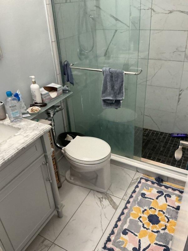 Removed two existing tankless toilets from a high-rise residential bathroom and installed two new tankless toilet units. Verified rough-in measurements at 14 inches, extended water supply lines as needed, and ensured proper elongated trap and spud connections with top-feed configuration. Completed installation with all fixtures tested and operational in modern bathroom with marble-patterned tile finishes.