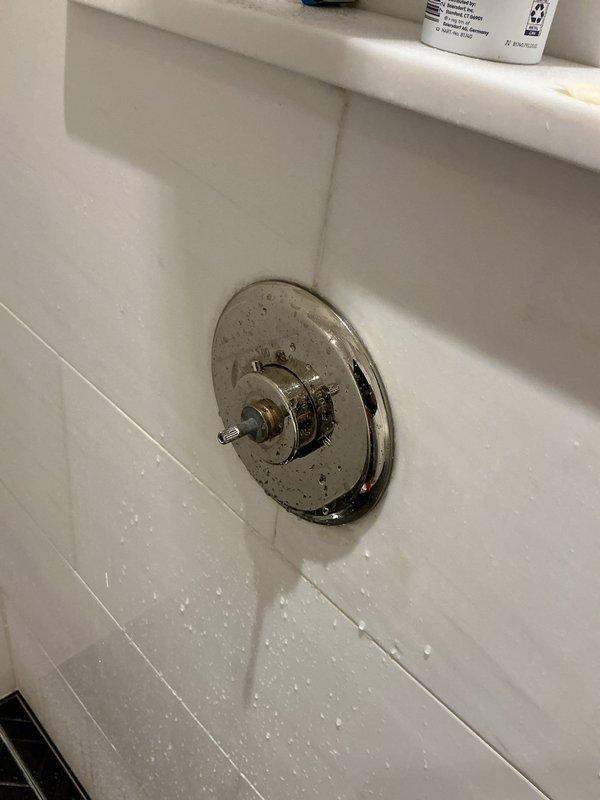 Responded to warranty callback for shower valve control lever that was damaged during previous repair attempt. Upon inspection, found valve stem exposed with escutcheon plate in place but operating handle completely removed. Identified replacement chrome valve handle and confirmed compatibility with existing trim assembly. Documented current condition showing valve stem protruding from wall-mounted fixture requiring proper handle reinstallation to restore full shower operation.