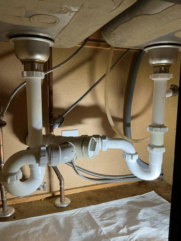 Responded to coach house residence for multiple plumbing concerns including leaky outdoor faucets, toilet issues, and kitchen sink drainage problems. Inspected and documented kitchen sink drain assembly beneath double-bowl sink, verifying PVC P-trap configuration and connections for periodic leak source. Assessed basement plumbing infrastructure, including copper supply lines with brass shutoff valves showing age-related deterioration and water staining on adjacent surfaces. Evaluated both outdoor hose bibs for replacement needs and verified operational status. Addressed two separate toilet malfunctions: one with active leak and second exhibiting intermittent water spurting during flush cycle. All plumbing systems inspected and photographed for comprehensive assessment of repair requirements.