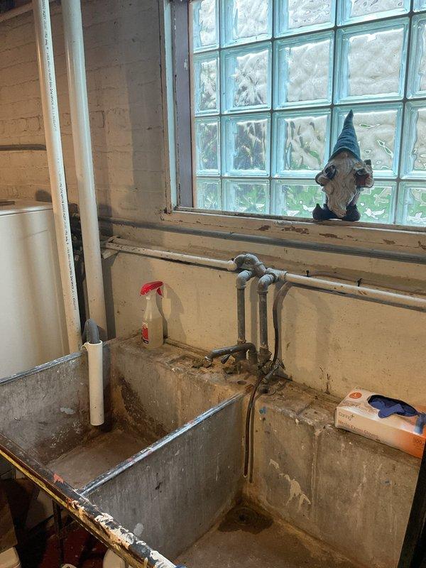 Responded to slow-draining laundry tub in basement. Conducted thorough inspection of existing metal laundry tub installation and drainage system. Observed aged galvanized plumbing with visible corrosion, oxidation, and deterioration throughout drain lines and supply connections. Assessed condition of concrete laundry tub platform and surrounding plumbing infrastructure. Documented existing configuration including drain assembly, trap connections, and washer supply lines. Provided estimate for complete laundry tub replacement, including removal of old metal tubs, installation of new laundry sink, replacement of deteriorated drain piping, and updated connections for washing machine hookups.