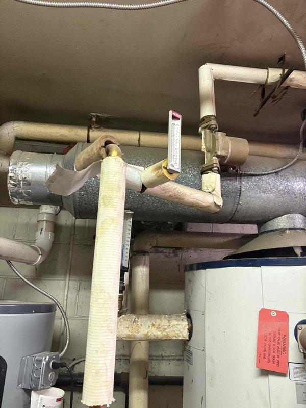 Conducted comprehensive assessment of existing water heating system in commercial building mechanical room. Evaluated current installation featuring aging insulated piping, multiple PVC drain lines, and conventional tank-type water heater alongside existing tankless unit. Documented equipment condition showing wear on pipe insulation, corroded fittings, and outdated components requiring replacement. Photographed existing copper supply lines, gas connections, venting systems, and electrical infrastructure to develop accurate replacement specifications. Provided detailed estimate for complete water heater replacement including removal of old equipment, installation of new unit with appropriate venting, updated copper piping connections, code-compliant gas line work, and proper condensate drainage system. Assessment included evaluation of mounting requirements, clearance specifications, and utility connections necessary for successful installation.