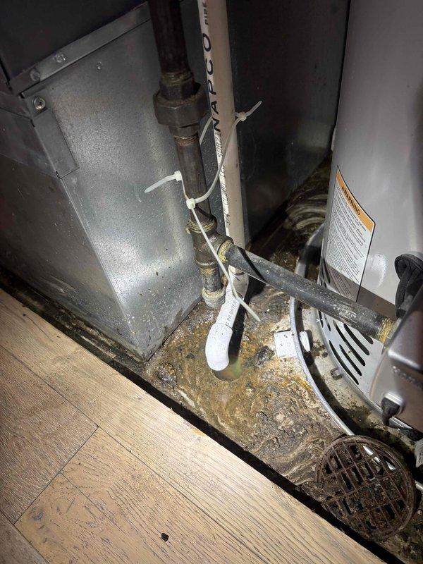 Inspected plumbing and HVAC infrastructure in mechanical space, documenting existing conditions of water heater, PVC drainage system, and associated piping components. Evaluated brass fittings, threaded connections, and metal pipes showing age-related oxidation, as well as cabinet-mounted hardware for potential service needs.