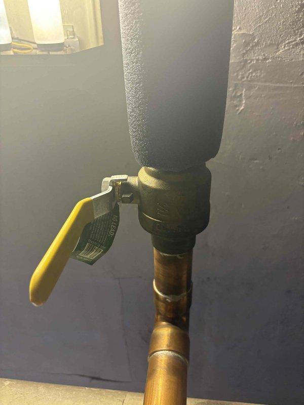 Conducted on-site assessment for water heater replacement in 12-unit residential building experiencing complete loss of hot water. Inspected existing tank-style water heater system installed in 2009, documented plumbing connections including ball valve shutoff with yellow lever handle and copper supply lines, and photographed current installation configuration to prepare comprehensive replacement estimate.