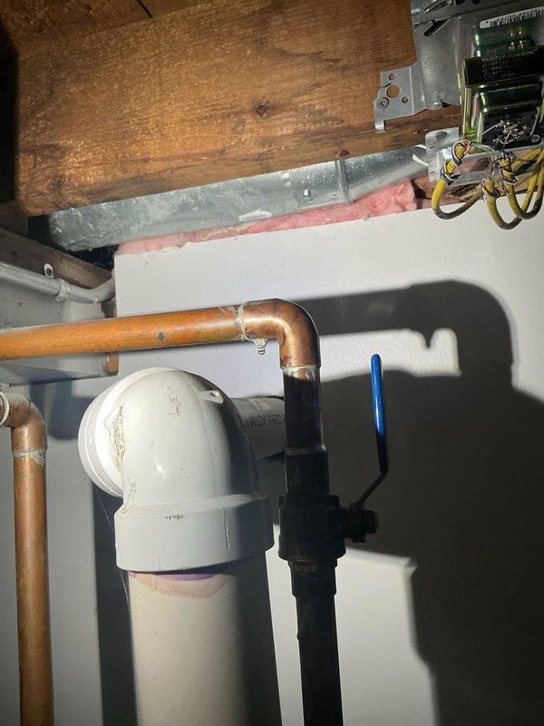 Conducted site visit to inspect water heater and associated plumbing systems in utility area. Upon examination, identified corroded temperature and pressure relief valve with significant rust and oxidation on brass-colored fittings and threaded connections. Inspected surrounding copper and PVC plumbing lines, HVAC condensate drain components, and mechanical systems in basement area. Documented current condition of water heater equipment, noting deteriorated valve requiring attention to prevent potential leaks or system failure. Photographed all findings for service records and provided recommendations for necessary repairs.