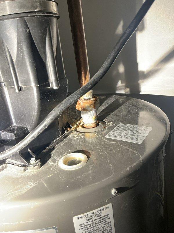 Conducted site visit to inspect water heater and associated plumbing systems in utility area. Upon examination, identified corroded temperature and pressure relief valve with significant rust and oxidation on brass-colored fittings and threaded connections. Inspected surrounding copper and PVC plumbing lines, HVAC condensate drain components, and mechanical systems in basement area. Documented current condition of water heater equipment, noting deteriorated valve requiring attention to prevent potential leaks or system failure. Photographed all findings for service records and provided recommendations for necessary repairs.
