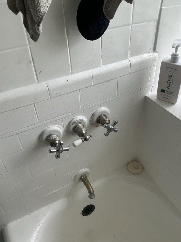 Responded to service call for multiple plumbing leaks affecting toilet, sink, and bathtub fixtures. Inspected bathroom plumbing system and identified sources of water leakage at each fixture. Documented existing conditions of bathtub area with wall-mounted three-handle faucet assembly and tub spout, as well as shower area with overhead fixture and glass block window installation.