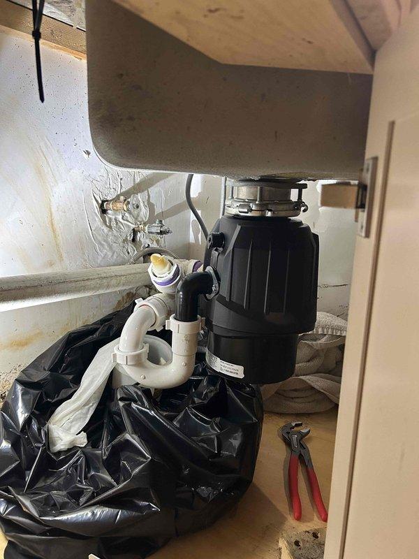 Responded to kitchen sink leak complaint and performed diagnostic inspection of under-sink plumbing assembly. Located source of leak at garbage disposal connection point and drain pipe fittings. Tightened disposal mounting hardware and replaced deteriorated gasket seal at disposal discharge connection. Inspected all PVC drain pipe joints and connections for proper sealing. Tested system under full water flow to verify leak resolution and confirm proper drainage function.