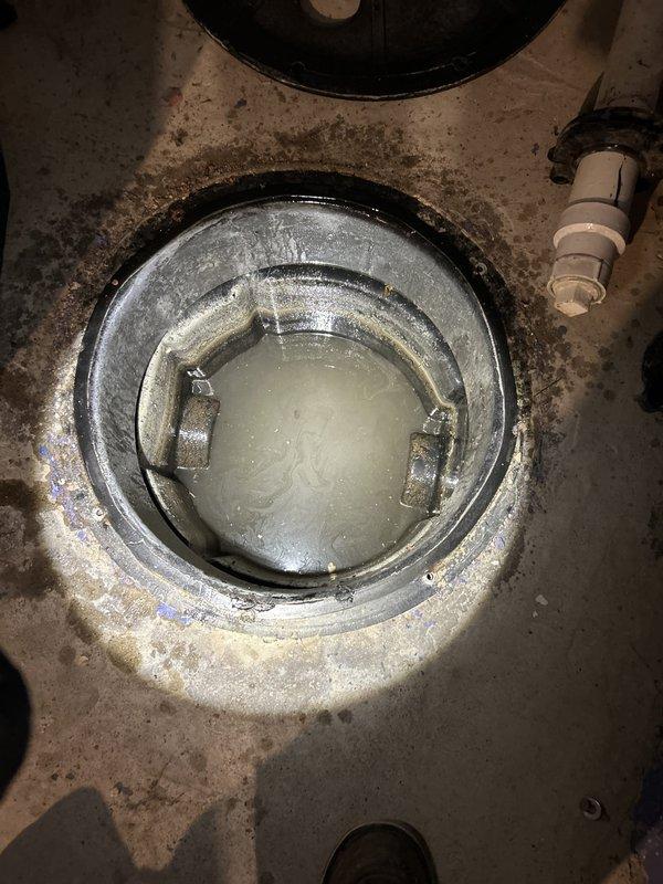 Responded to service call for non-operational sump pump system in basement utility area. Upon arrival, conducted visual inspection of sump basin and pump assembly. Found pump mechanism with corroded mounting brackets and mineral deposit buildup on metallic support structure, indicating extended exposure to groundwater conditions. Standing water present in basin with visible sediment accumulation. Assessed pump functionality and drainage system integrity, including examination of discharge piping and PVC connections. Performed diagnostic evaluation of pump motor and float switch operation. Documented existing conditions of concrete floor installation, basin seal integrity, and overall system configuration for maintenance records.