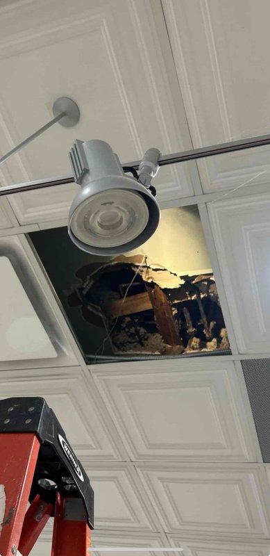 Responded to callback to verify leak resolution status. Conducted thorough inspection of previously reported water intrusion area affecting ceiling structure. Documented existing ceiling damage with exposed framing, insulation, and deteriorated materials near track lighting fixture. Inspected mechanical space and examined insulated refrigerant lines, HVAC components, and surrounding wooden structural elements showing signs of previous moisture exposure and age-related deterioration. Confirmed current status of leak repairs and provided photographic documentation of affected areas for business owner review and verification of remediation effectiveness.