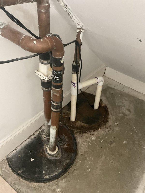 Replaced aging sump pump system with new primary pump and battery backup unit in basement utility area. Installation included new copper discharge piping with check valve assemblies, PVC drain connections, and electrical wiring with backup power integration to ensure continuous operation during power outages.