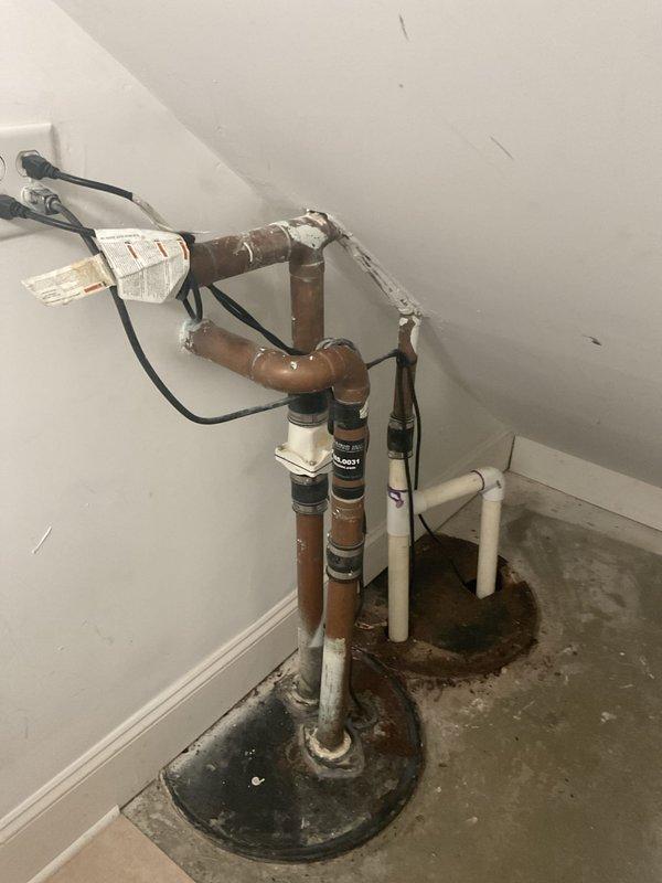 Replaced aging sump pump system with new primary pump and battery backup unit in basement utility area. Installation included new copper discharge piping with check valve assemblies, PVC drain connections, and electrical wiring with backup power integration to ensure continuous operation during power outages.