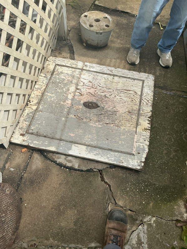 Responded to service call for catch basin repair assessment. Upon arrival, inspected exterior catch basin access point and internal structure. Documented extensive deterioration of concrete catch basin components, including severe cracking, structural separation, and significant corrosion of internal reinforcement materials. Access cover showed advanced weathering with paint failure and wood deterioration. Internal inspection revealed compromised concrete integrity with visible voids, exposed rusted rebar, and multiple fracture points throughout the basin structure. Photographed all damage for estimate preparation and provided homeowners with detailed assessment of necessary repairs to restore proper drainage function and structural integrity.