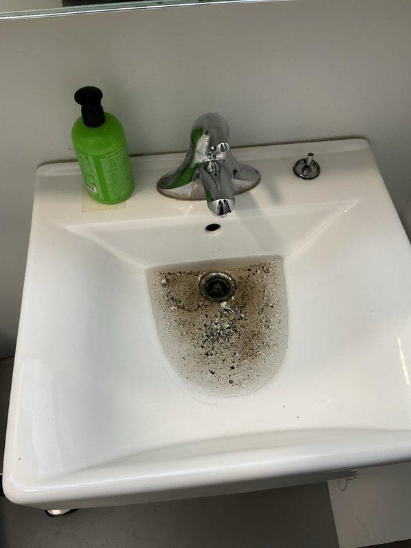 Responded to service call for clogged bathroom sink. Upon arrival, found significant staining and mineral deposits around drain area indicating long-term drainage issues. Cleared blockage from P-trap and drain line using appropriate tools and techniques. Tested water flow after clearing obstruction; drainage restored to normal function. Sink now draining properly with no standing water or slow flow issues.