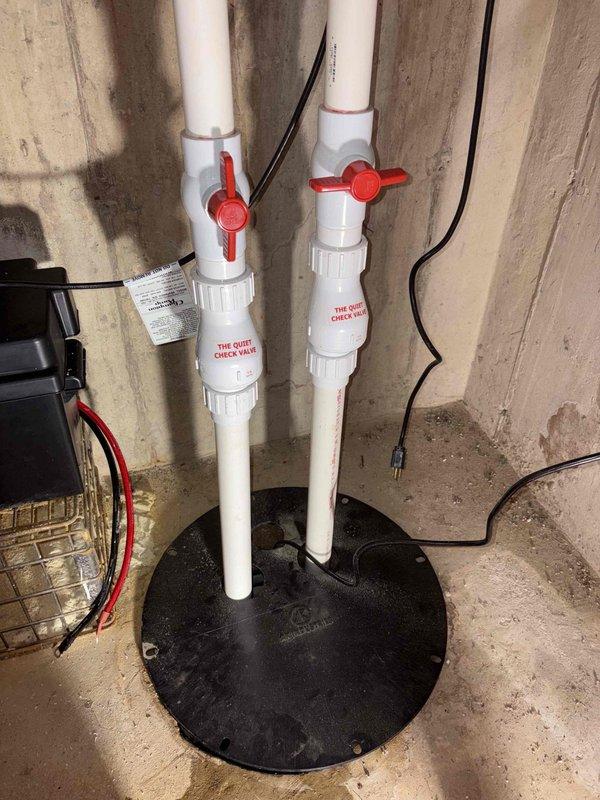 Responded to service call regarding backup battery alarm sounding on sump pump system installed in 2024. Upon arrival, inspected dual-pump configuration with check valves and battery backup unit. Examined battery connections, tested alarm functionality, and verified proper operation of primary and backup pumps. Determined alarm was triggered by battery condition requiring attention. Reset alarm system, checked all electrical connections, and confirmed both pumps cycling correctly with proper discharge through PVC piping system.