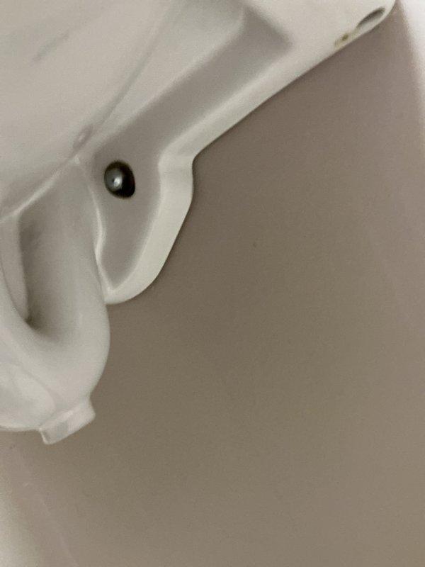 Responded to complaint of urinal backing up in commercial shop restroom. Upon inspection, found wall-mounted porcelain urinal with drainage issues. Cleared obstruction from drain line and verified proper flow through flush valve system. Tested fixture operation to confirm complete drainage and proper function of chrome flush valve assembly. Unit restored to normal working condition.
