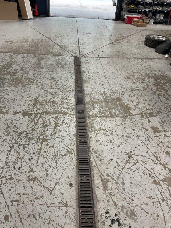 Responded to customer report of main drain backup. Upon arrival, located floor drain with linear trench grate system in garage area. Assessed drainage system for blockage causing backup condition. Cleared obstruction from main drain line, restoring proper flow and eliminating backup issue. Verified system functionality upon completion.