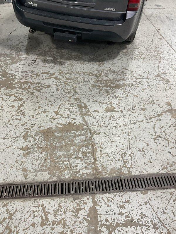 Responded to customer report of main drain backup. Upon arrival, located floor drain with linear trench grate system in garage area. Assessed drainage system for blockage causing backup condition. Cleared obstruction from main drain line, restoring proper flow and eliminating backup issue. Verified system functionality upon completion.