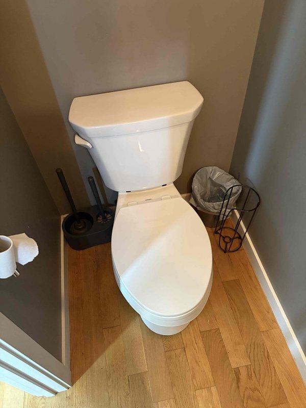 Completed toilet installation in residential bathroom. Installed new white two-piece porcelain toilet with standard floor-mounted configuration, ensuring proper positioning within the bathroom alcove and secure connection to existing plumbing. Verified proper operation and conducted final inspection of the installation.