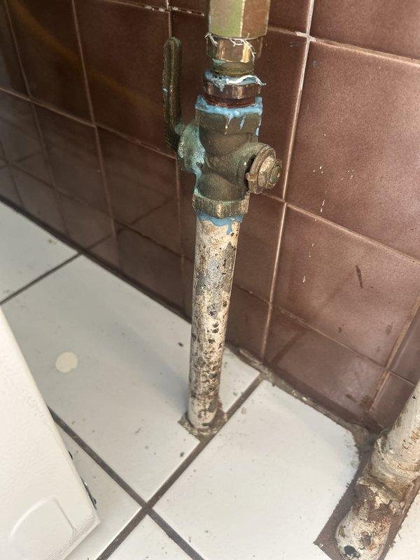Responded to emergency gas leak situation where utility company had shut off gas service to the apartment for three days. Located and identified gas leak in basement area originating from severely corroded plumbing fixture assembly mounted on wall. The fixture displayed extensive oxidation with green-blue patina on brass components and heavy surface corrosion on vertical piping, indicating long-term deterioration and moisture exposure. Documented existing conditions with photographs showing compromised valve mechanism and connection points. Assessed basement environment and adjacent living spaces to ensure safety protocols were maintained throughout inspection and repair process.