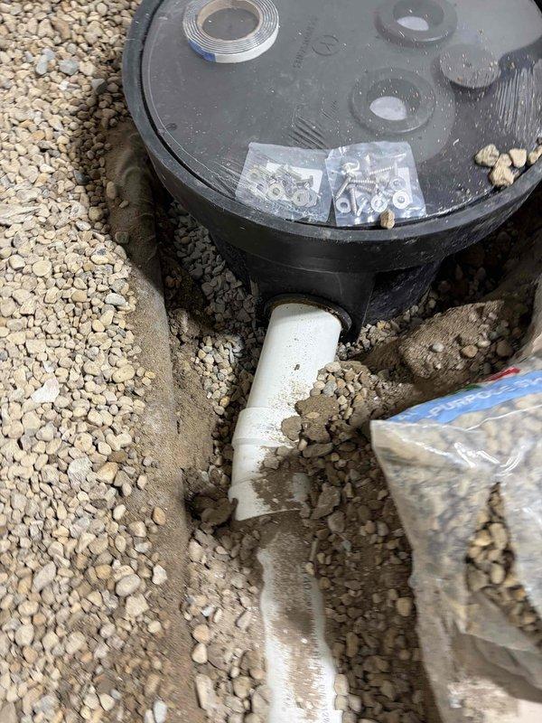 Responded to flooding emergency in basement utility room with several inches of standing water accumulation. Assessed drainage system and floor drain functionality to identify source of water intrusion. Inspected outdoor septic or water management tank system with multiple access ports, verified PVC discharge line connections, and documented condition of installation in gravel bed to ensure proper drainage operation and prevent future flooding incidents.