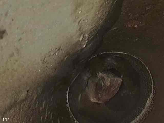 Inspected and documented plumbing conditions in crawlspace and basement areas. Photographed existing insulation material showing signs of moisture exposure and deterioration in crawlspace, along with floor drain assembly embedded in concrete basement floor displaying significant wear, staining, and debris accumulation. Repair recommendations provided to address drainage concerns and moisture-related issues affecting building materials.