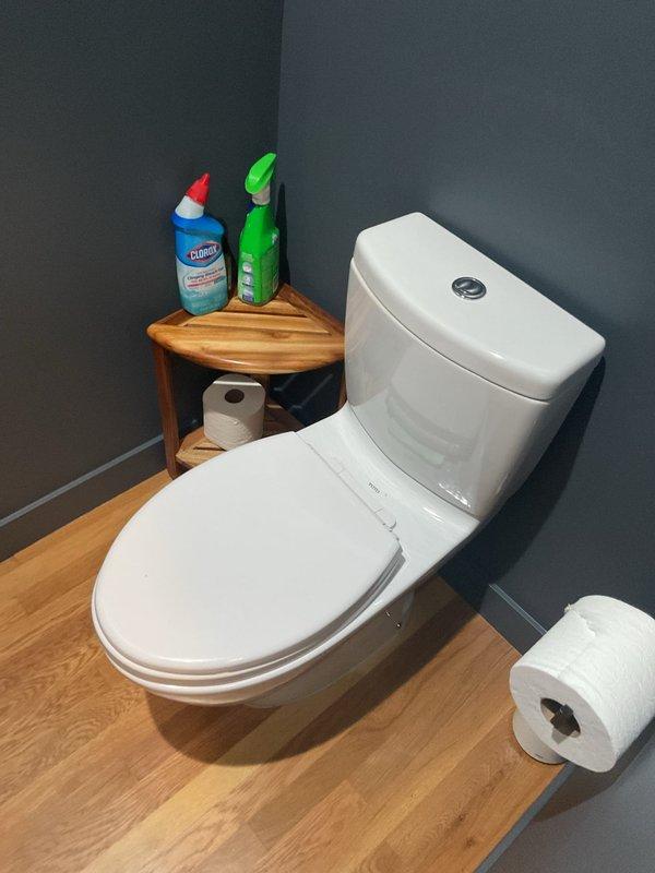 Responded to service call for odor complaint related to toilet fixture. Upon arrival, performed thorough inspection of TOTO two-piece toilet with dual-flush mechanism. Examined wax ring seal, flange connection, and trap for potential sources of sewer gas infiltration. Verified proper operation of flush mechanism and water seal in bowl. Documented existing bathroom conditions including modern one-piece toilet installation with corner storage area containing cleaning supplies. No immediate mechanical failures or leaks detected during visual inspection.
