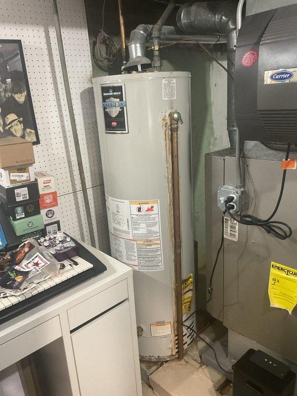 Conducted on-site assessment of existing 40-gallon residential water heater, approximately 10 years old, for replacement estimate. Evaluated current tank-type water heater installation in utility room, documenting copper supply line connections, venting configuration, and existing plumbing infrastructure. Noted visible corrosion on vertical copper piping and assessed compatibility requirements for potential tankless water heater conversion, including gas line capacity, electrical requirements, and venting modifications that would be necessary for upgraded equipment installation.