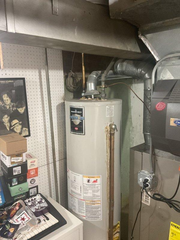 Conducted on-site assessment of existing 40-gallon residential water heater, approximately 10 years old, for replacement estimate. Evaluated current tank-type water heater installation in utility room, documenting copper supply line connections, venting configuration, and existing plumbing infrastructure. Noted visible corrosion on vertical copper piping and assessed compatibility requirements for potential tankless water heater conversion, including gas line capacity, electrical requirements, and venting modifications that would be necessary for upgraded equipment installation.